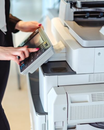 Woman standing and pressing button on a copy machine in the office